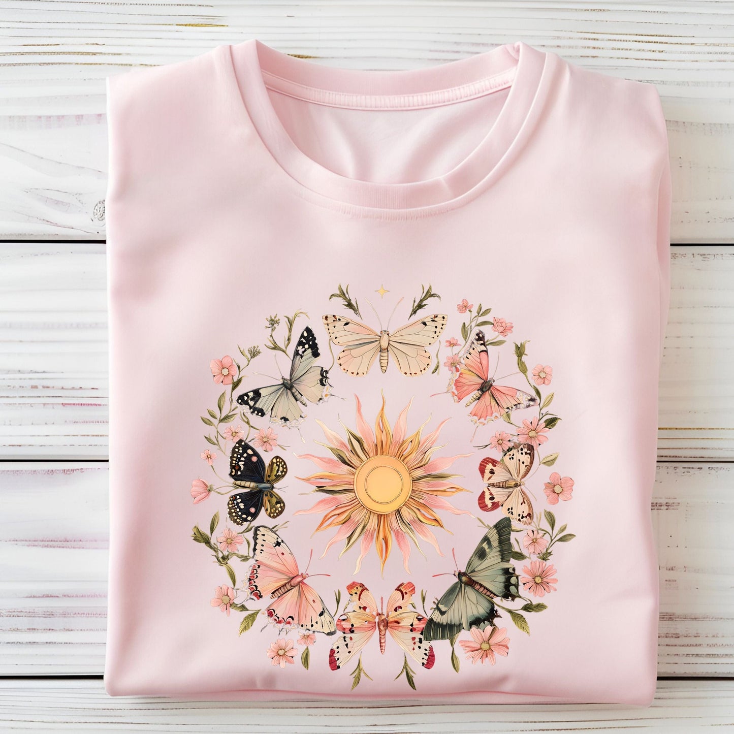 Pink long sleeve t-shirt with butterfly and floral design on a wooden surface