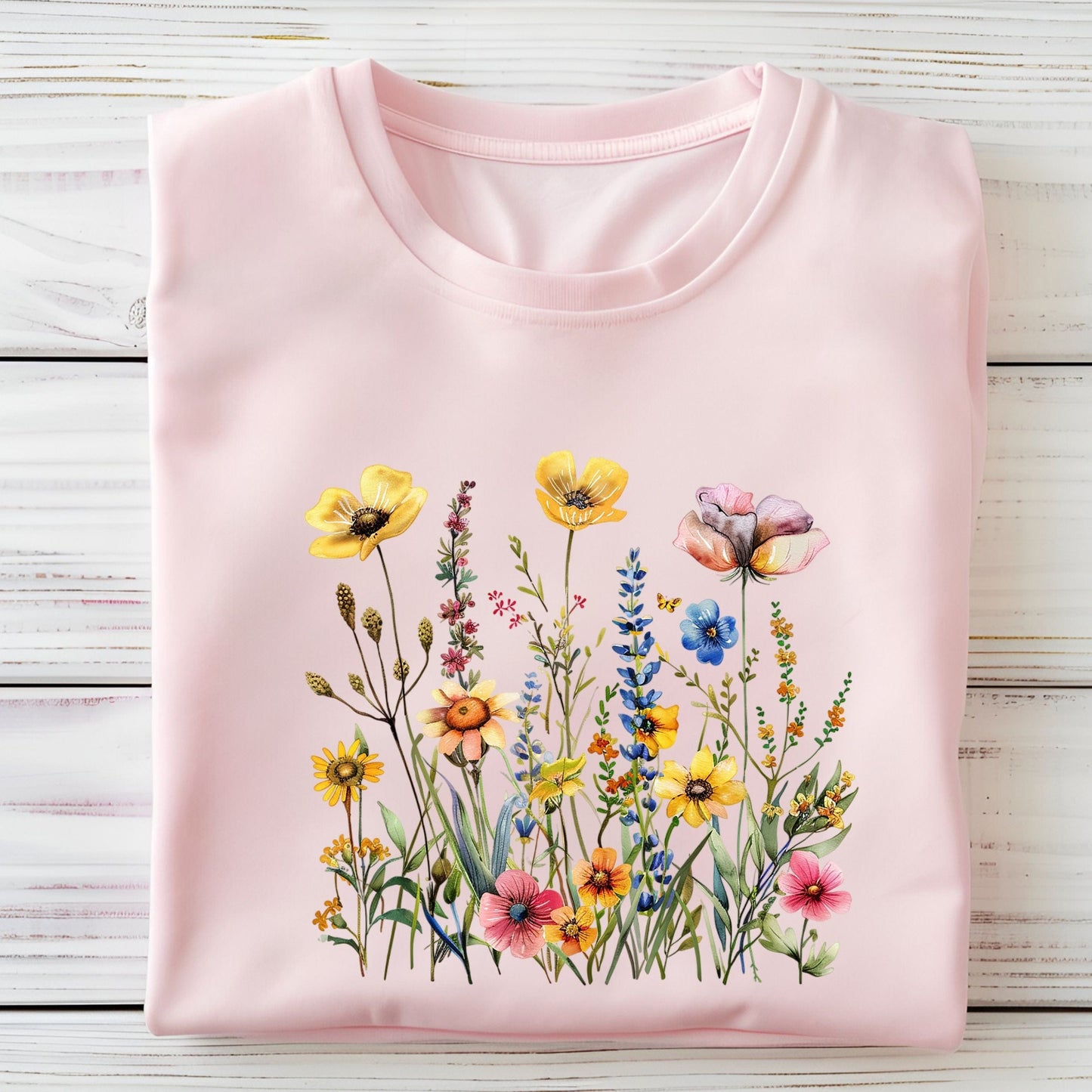 Pink t-shirt with a colorful floral design on a wooden surface