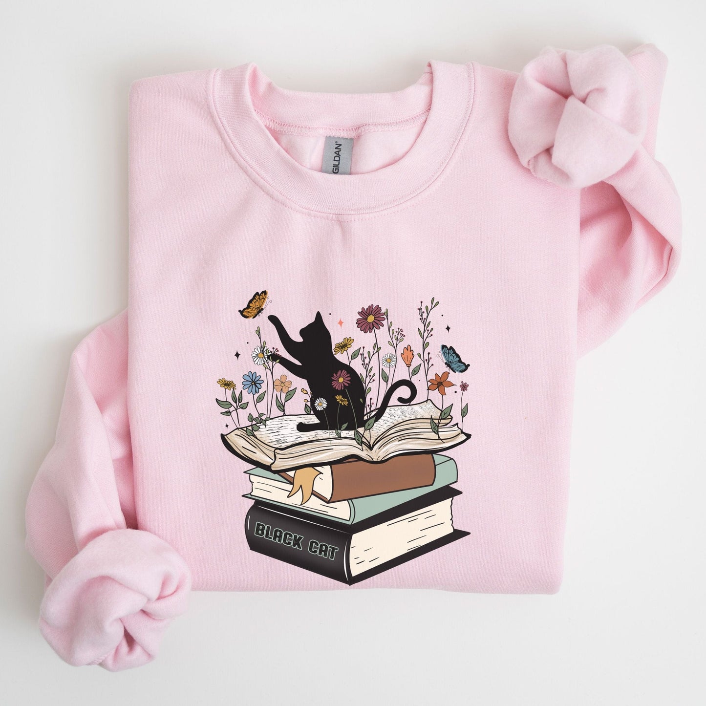 Pink sweatshirt with a cat and book design on a white background