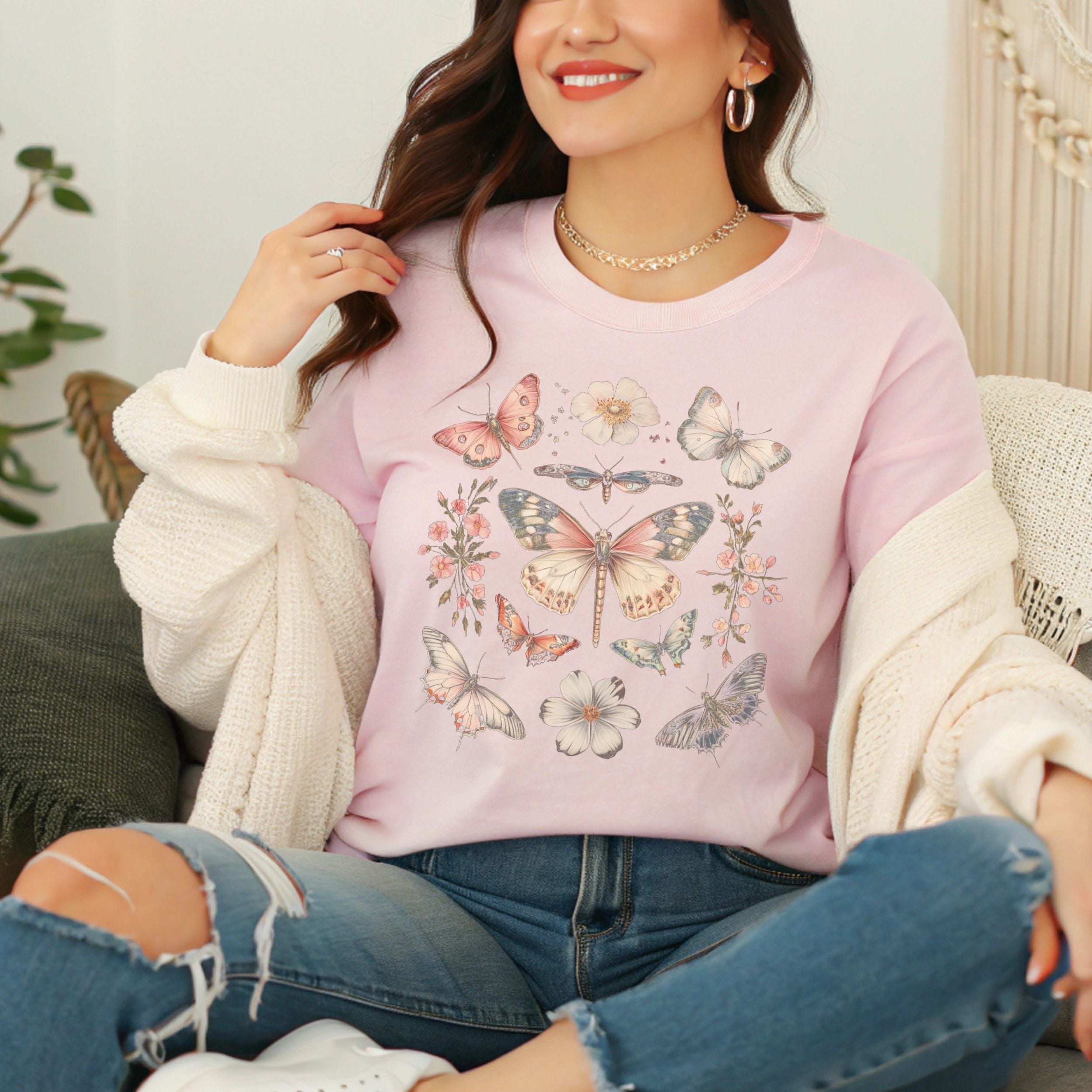 Woman wearing a soft pink t-shirt with butterfly designs, sitting on a couch.