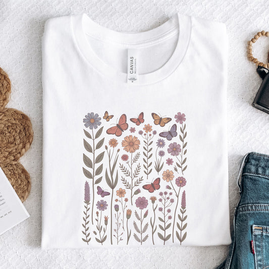 White long sleeve t-shirt with floral and butterfly design on a textured surface