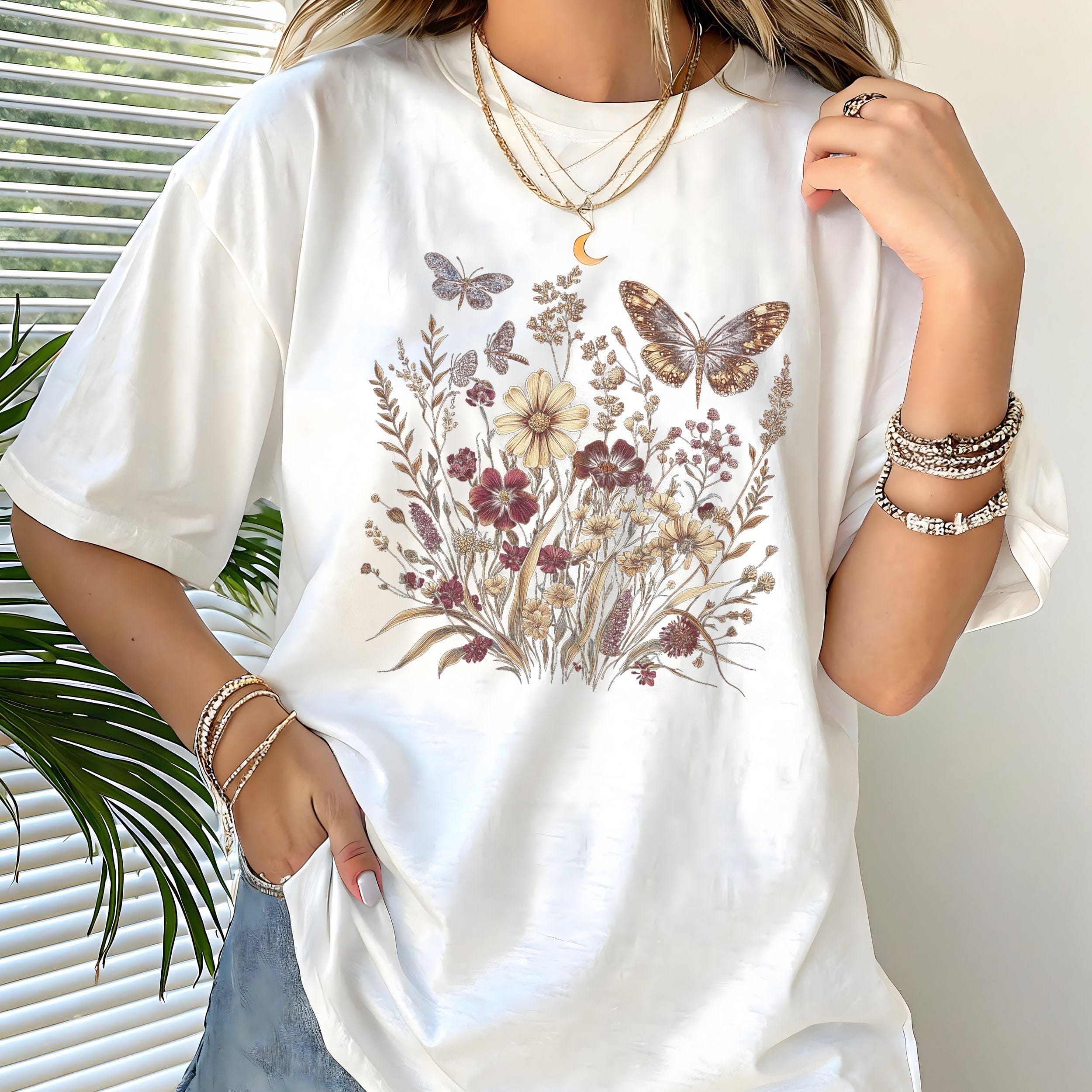 Person wearing a white t-shirt with floral and butterfly design, standing indoors.