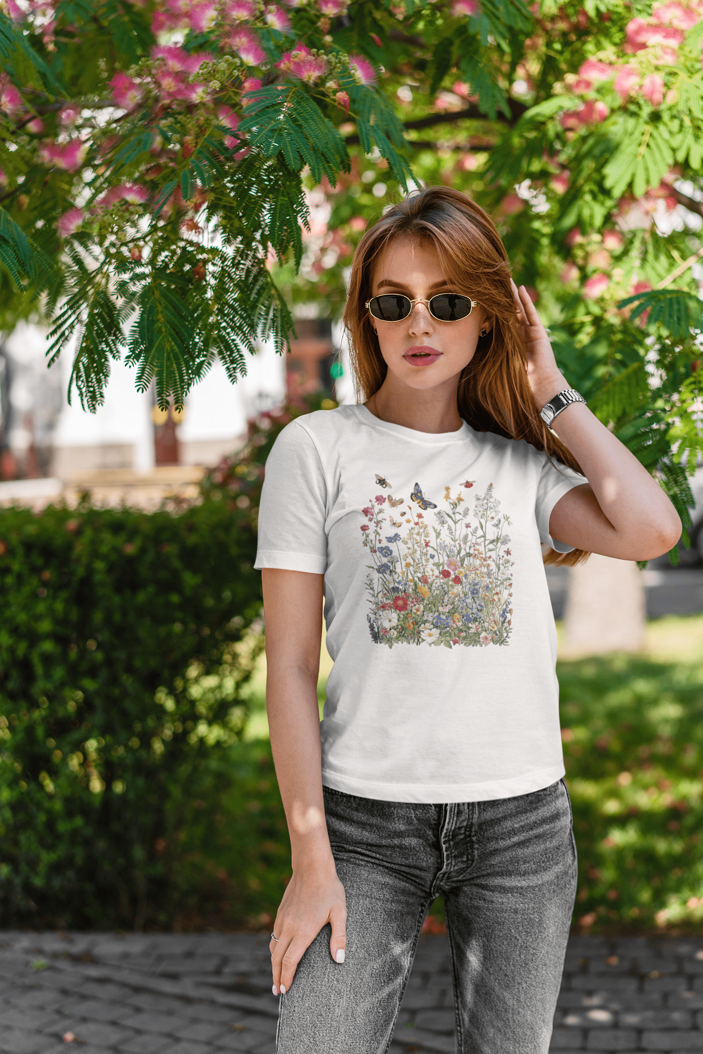Woman wearing a white t-shirt with a colorful graphic design outdoors.