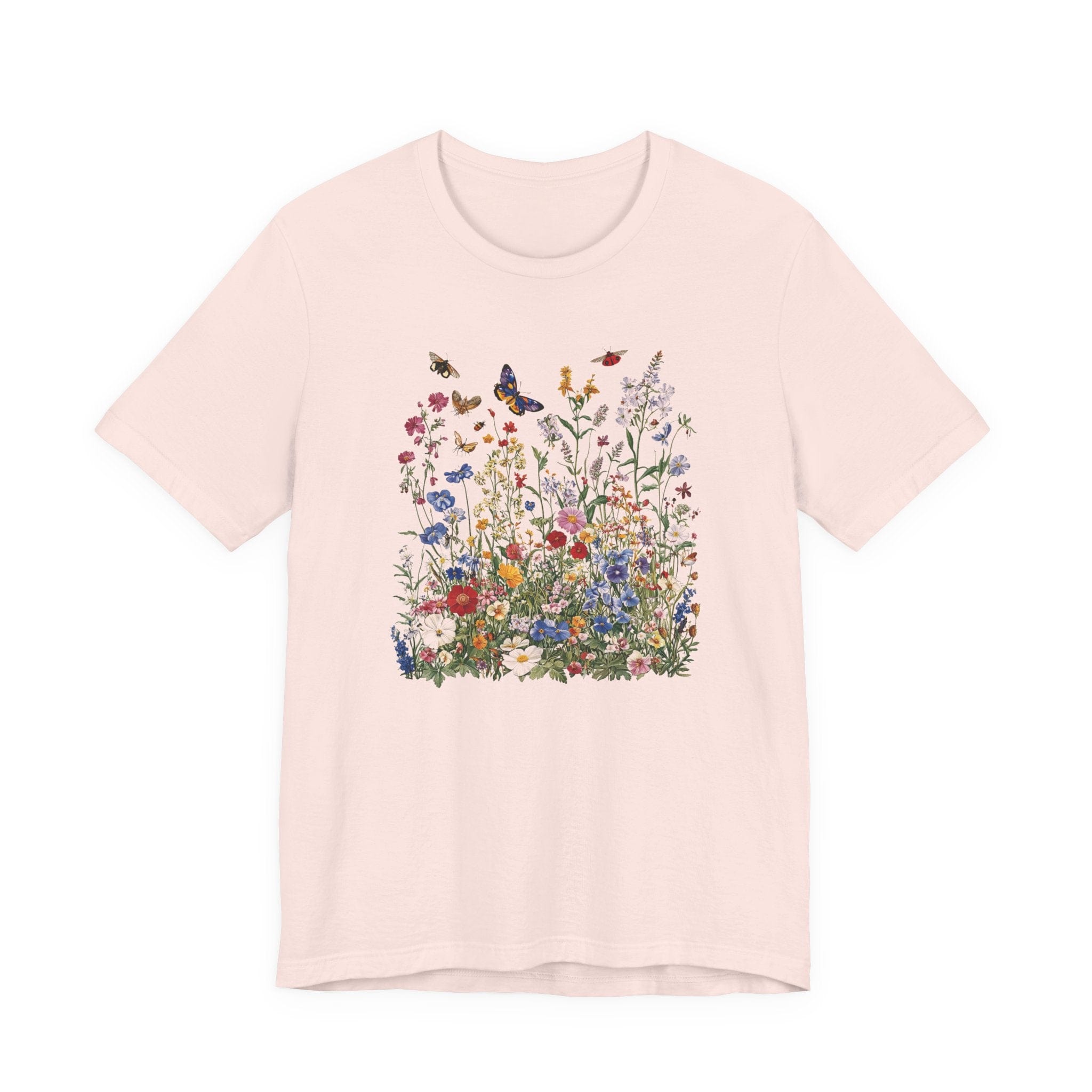Flat lay of soft pink t-shirt featuring colorful wildflower meadow with butterflies
