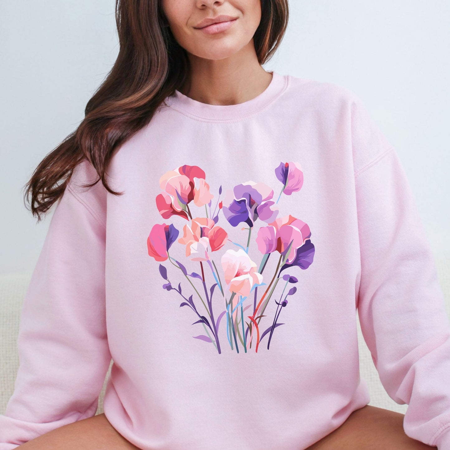 Person wearing a pink sweatshirt with a floral design on a light background