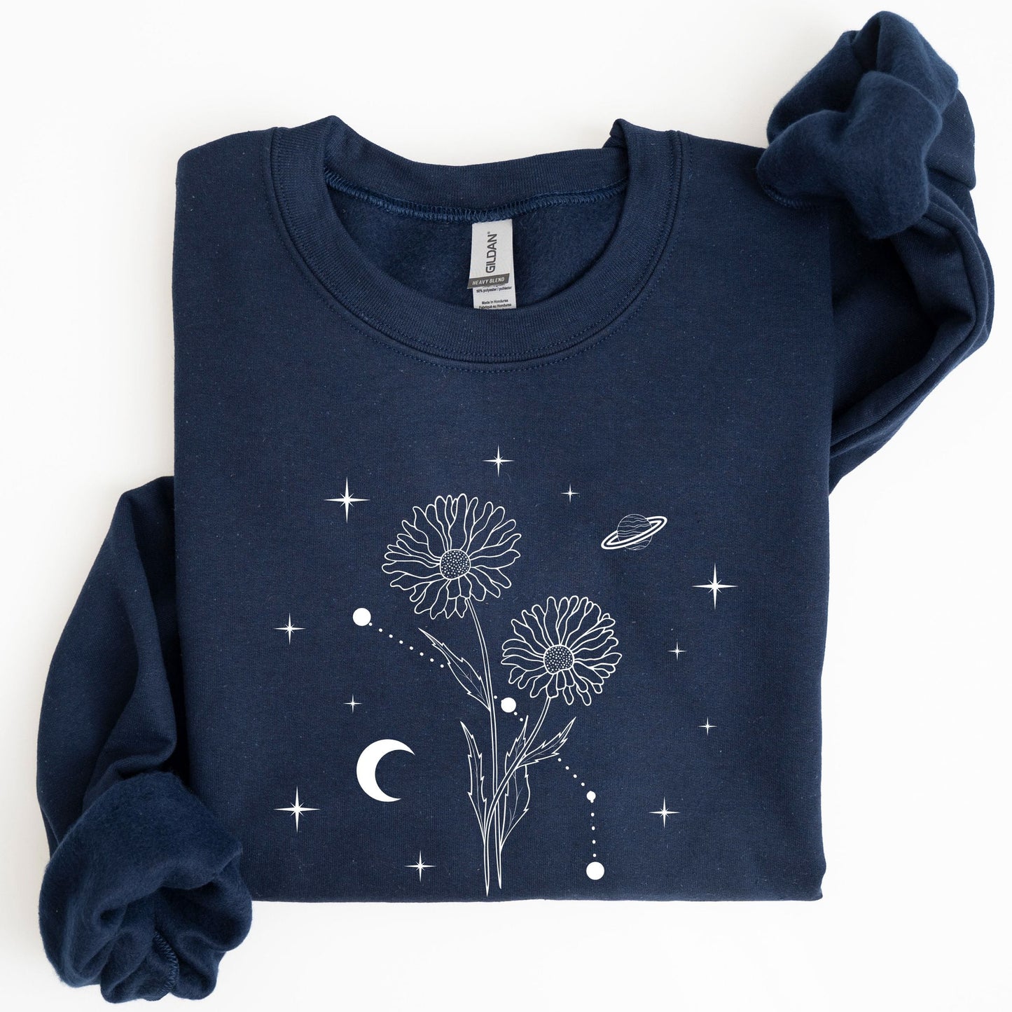 Folded navy blue sweatshirt with white floral and celestial design on a white background