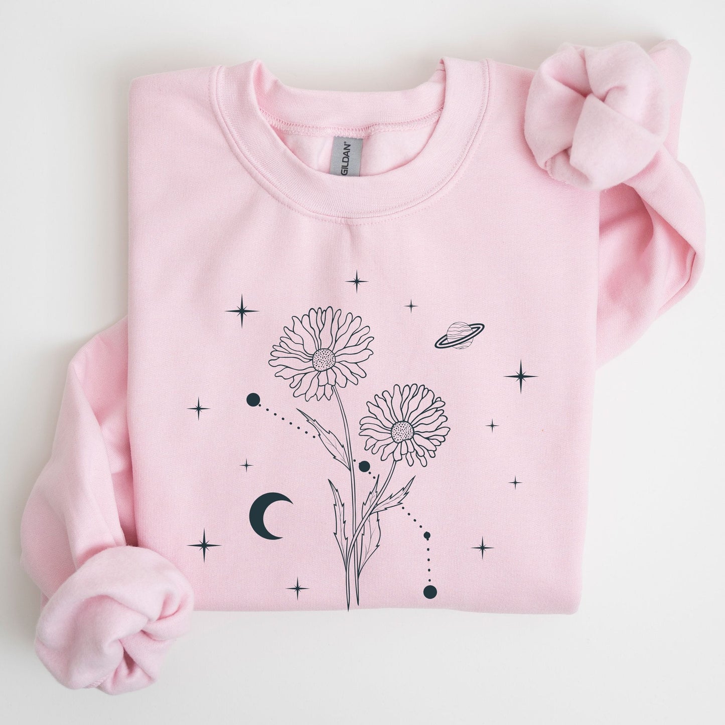 Pink sweatshirt with floral and celestial design on a light gray background