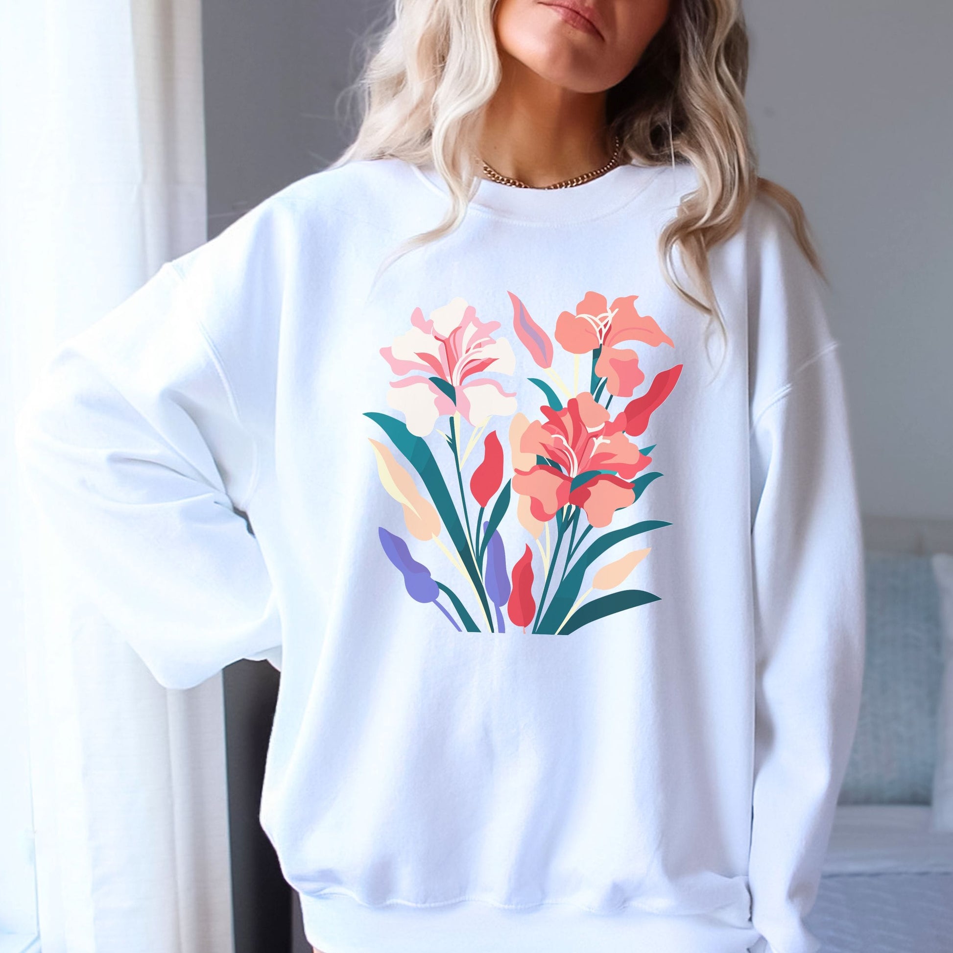 White sweatshirt with colorful floral design worn by a person indoors.