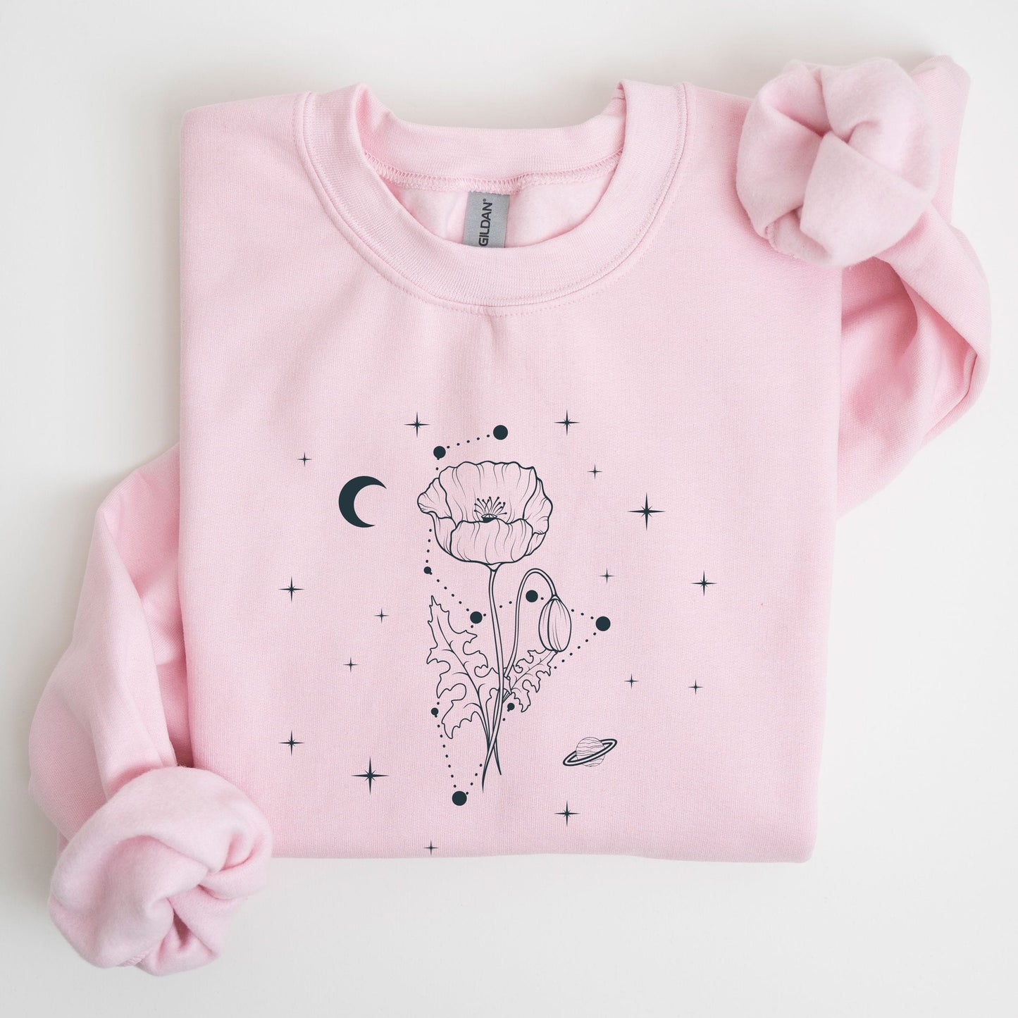 Pink sweatshirt with black floral and celestial design on a light gray background