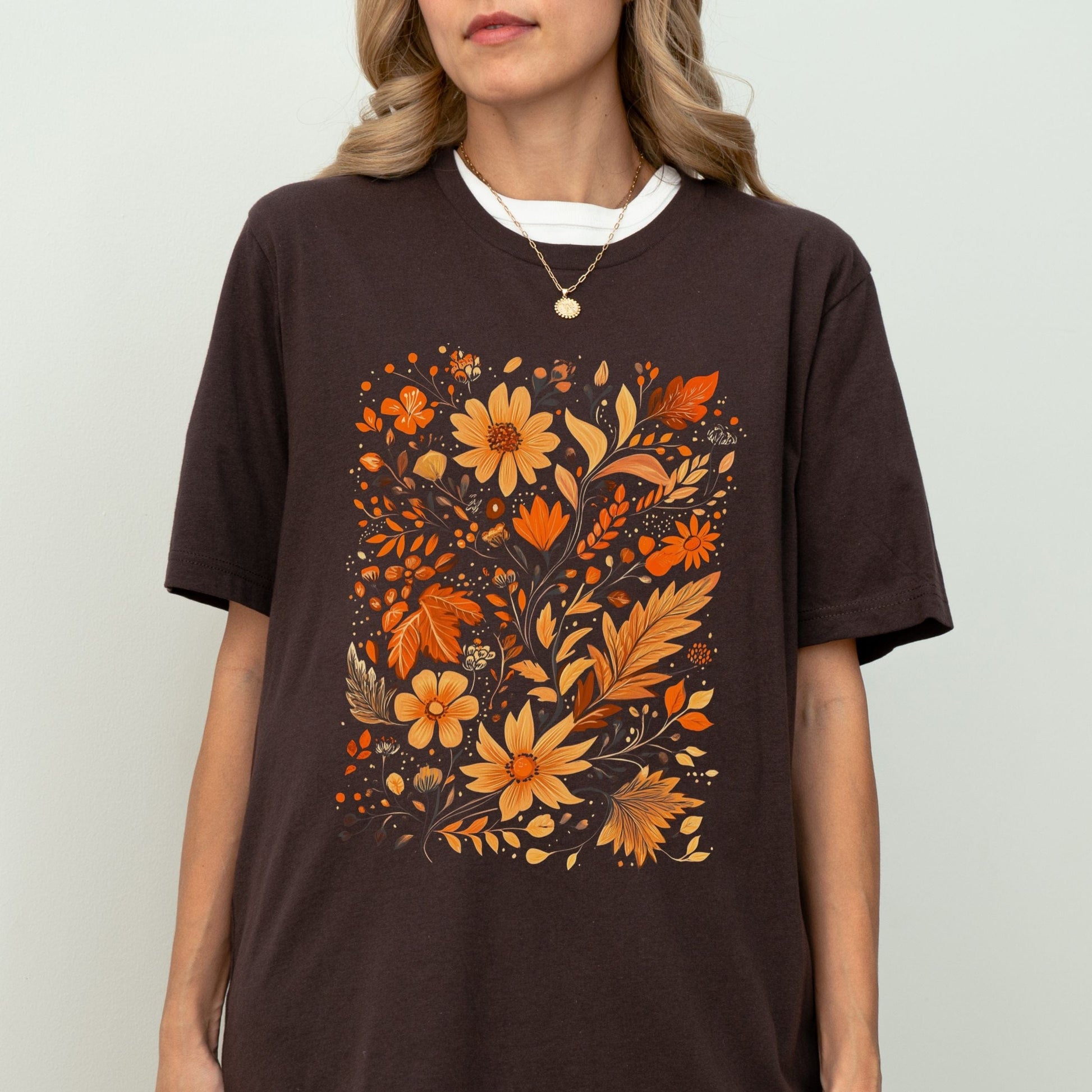 Person wearing a brown t-shirt with orange floral design on a plain background