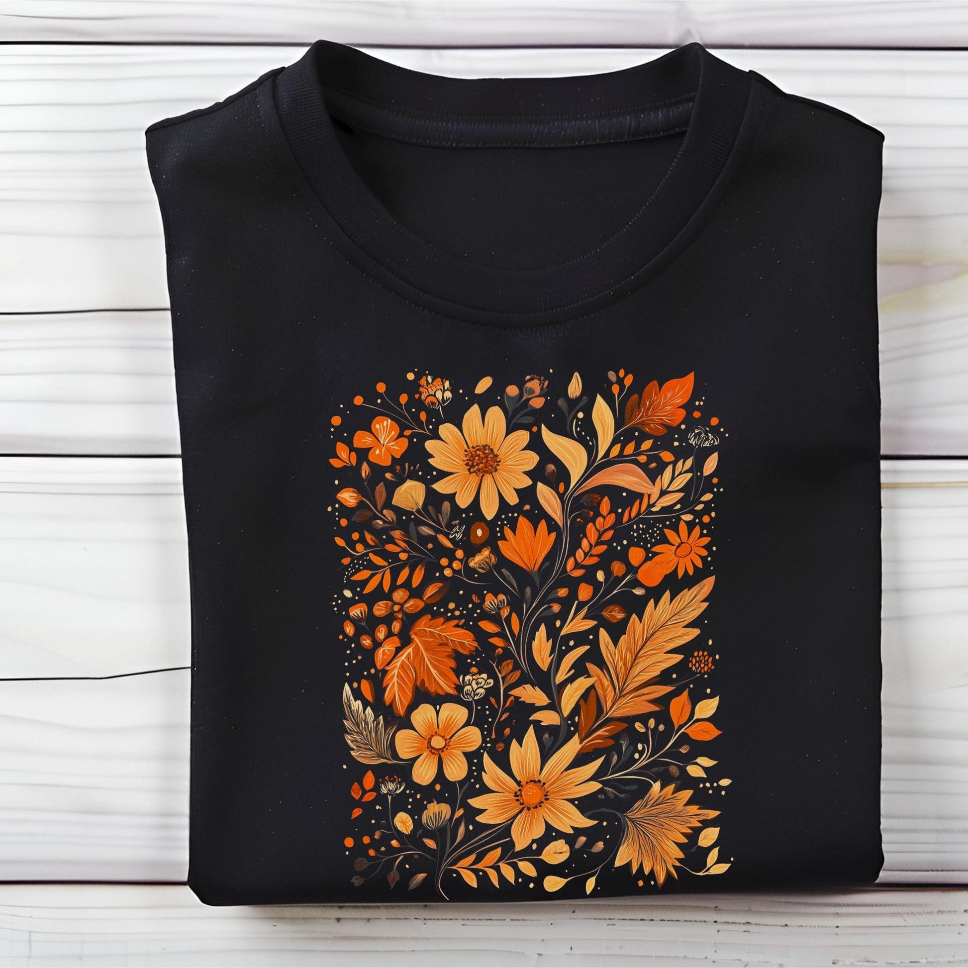 Flat lay of black t-shirt featuring orange and gold autumn floral design