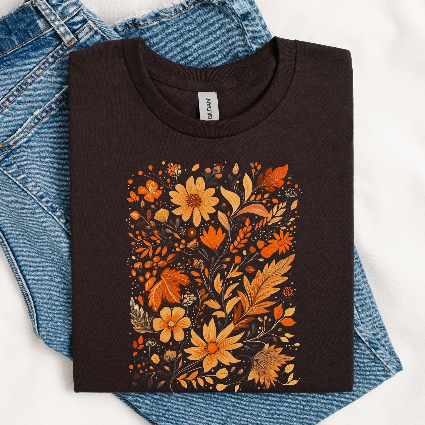 Flat lay of brown t-shirt featuring orange and gold autumn floral design
