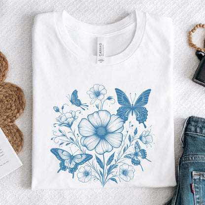 White t-shirt with blue floral and butterfly design on a white surface.