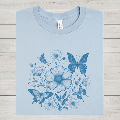 Blue t-shirt with blue floral and butterfly design on a wooden surface