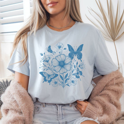 Person wearing a light blue t-shirt with blue floral and butterfly design.