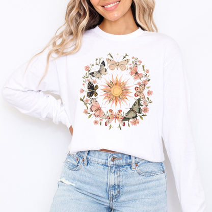 Person wearing a white long sleeve t-shirt with a colorful sun and butterfly design.