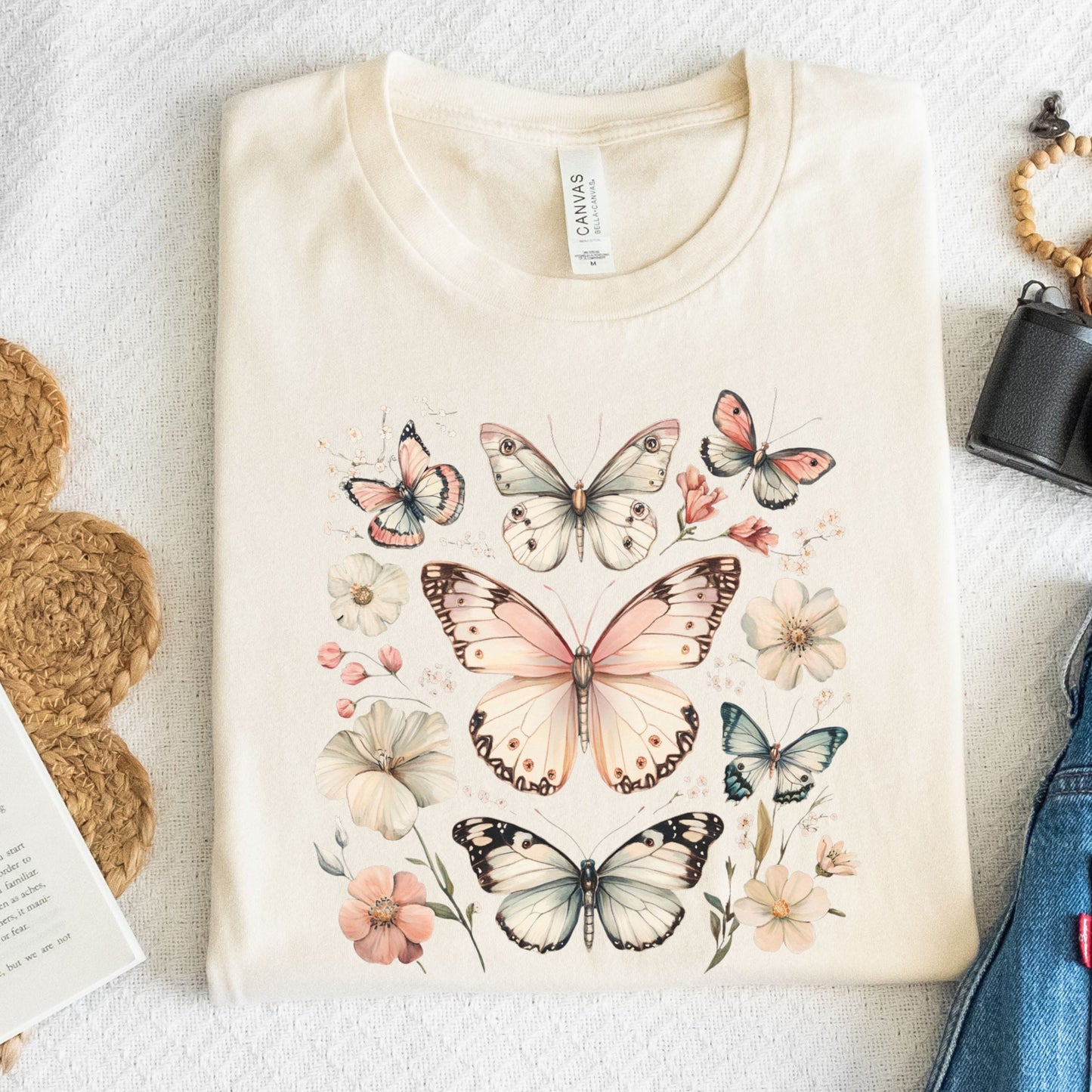 Beige t-shirt with butterfly and floral design on a textured surface