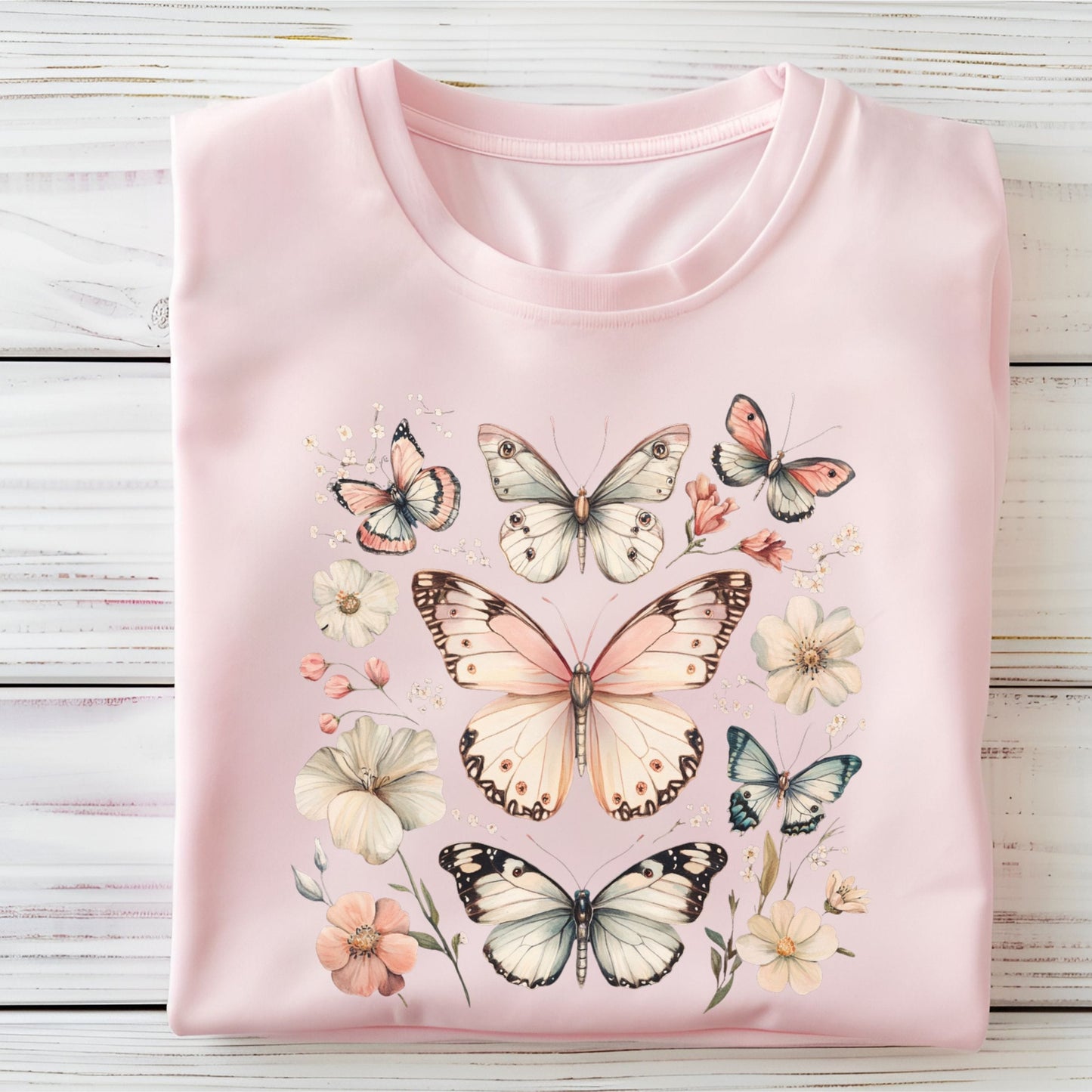 Pink t-shirt with butterfly and flower designs on a wooden surface