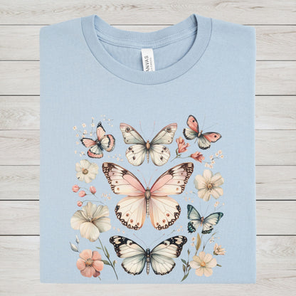 Light blue t-shirt with butterfly and flower design on a wooden surface