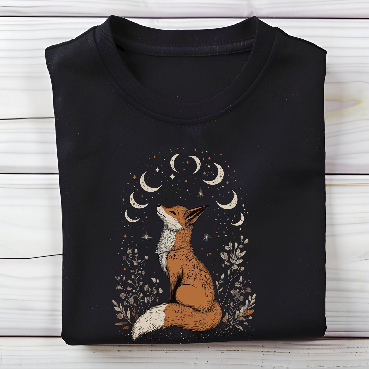 Black t-shirt with a fox and moon design on a wooden surface