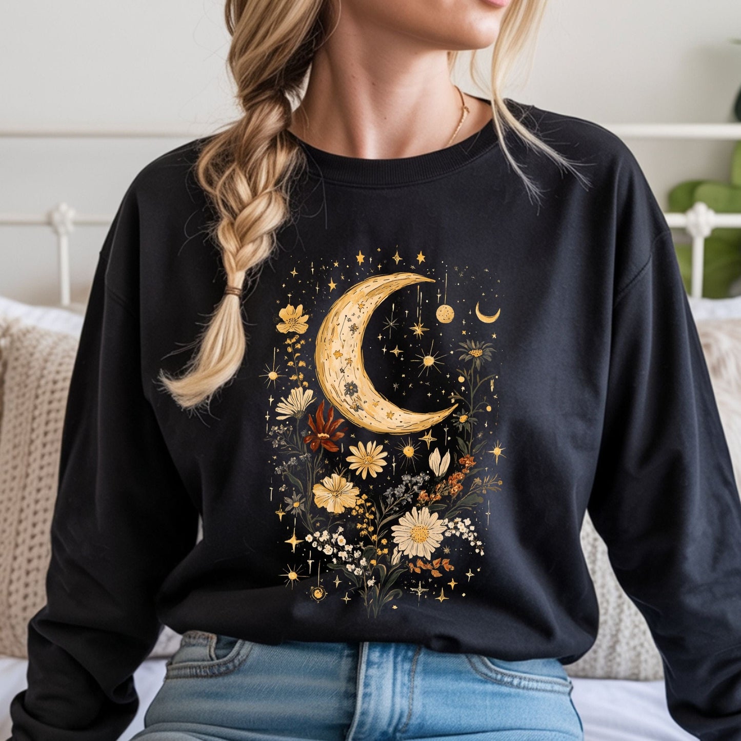 Person wearing a black long sleeve tee with a moon and floral design.