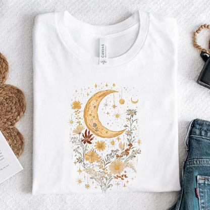 White t-shirt with a decorative moon and floral design on a textured surface.