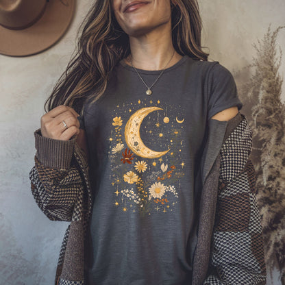Woman wearing a dark gray t-shirt with a celestial design, holding a brown jacket.