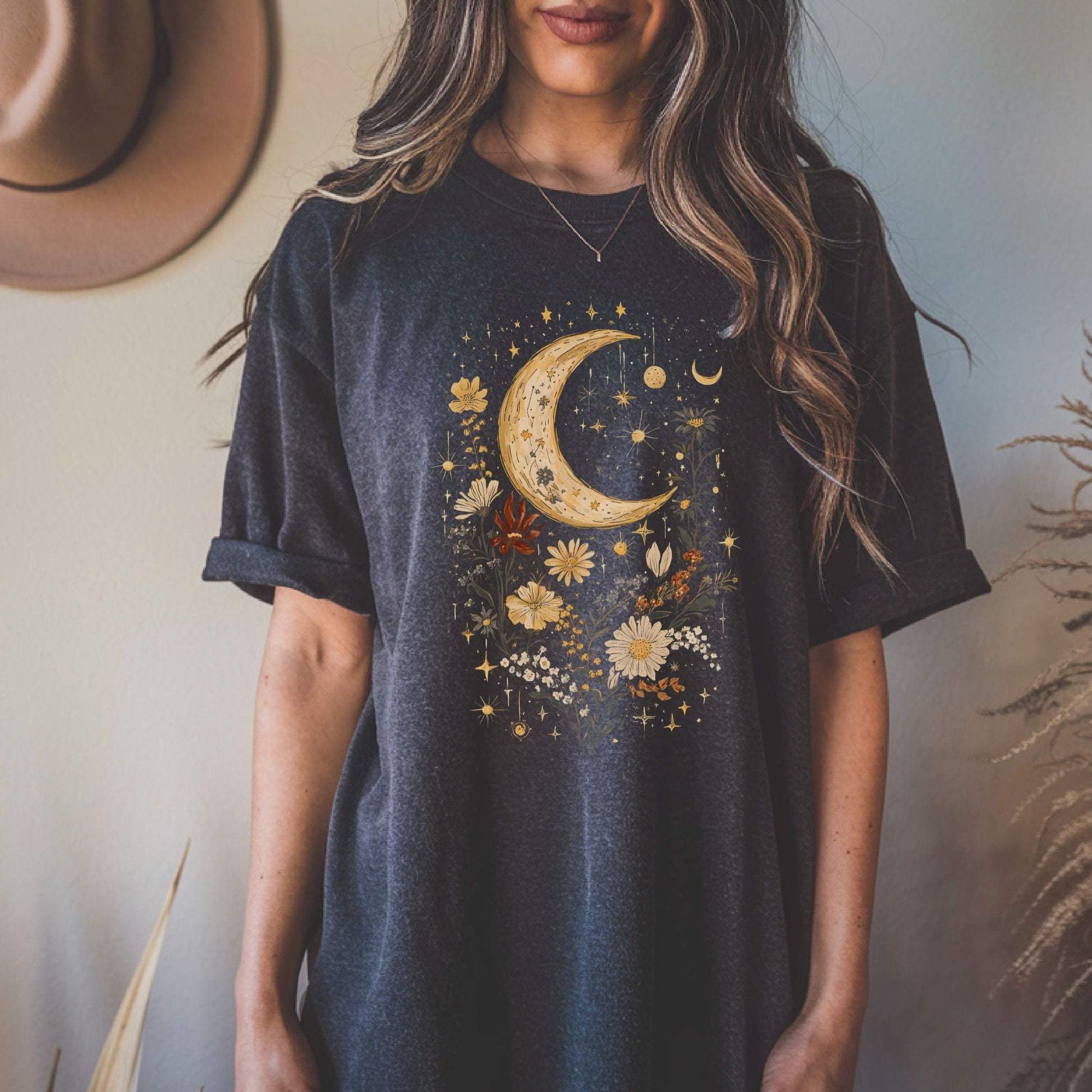 Person wearing a dark grey heather t-shirt with a celestial design featuring a moon, stars, and flowers.