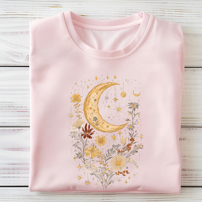 Pink t-shirt with a moon and floral design on a wooden surface