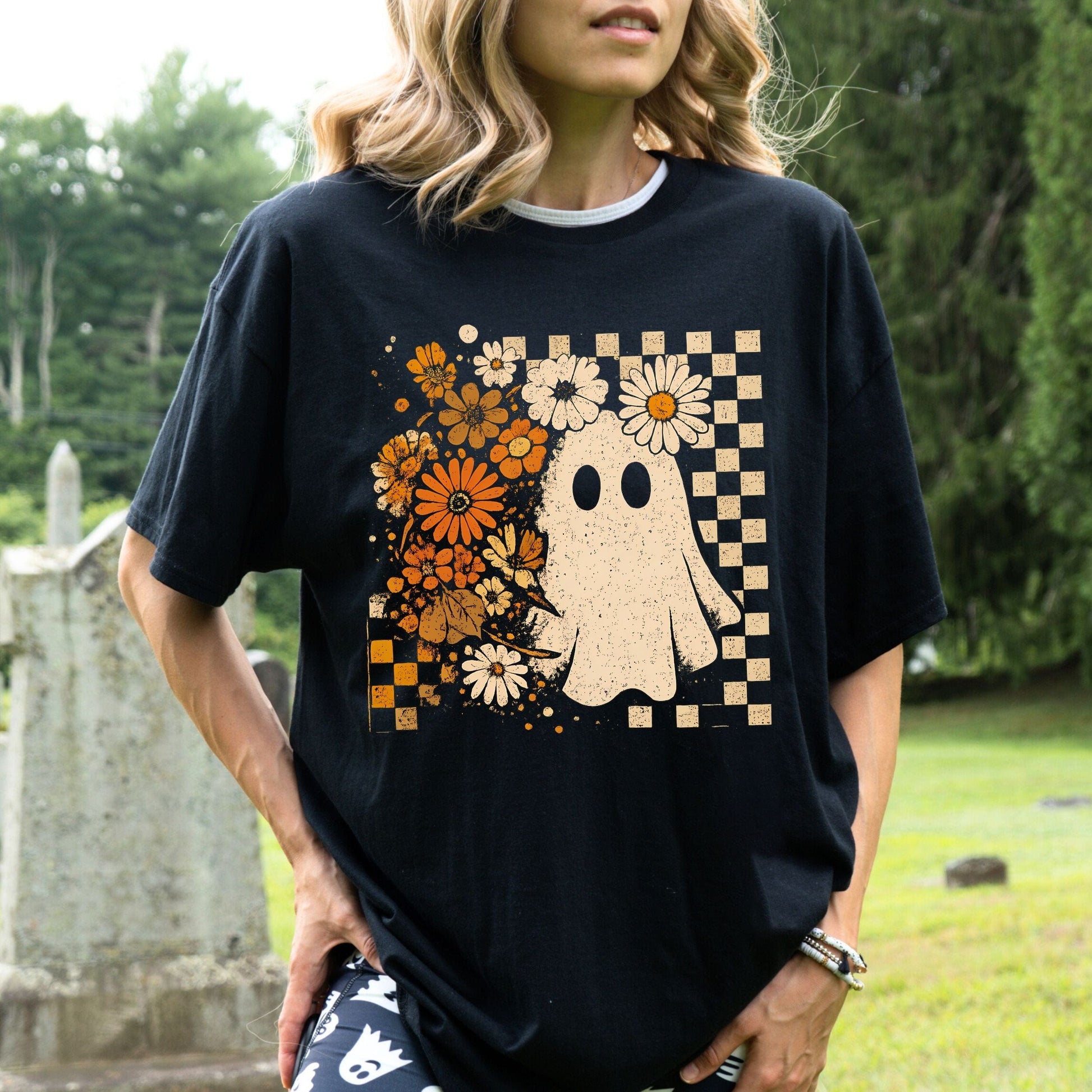Person wearing a black t-shirt with a ghost and floral design outdoors.