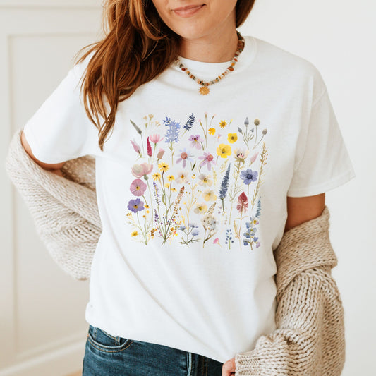 Person wearing a white t-shirt with floral design, beige cardigan, and blue jeans.