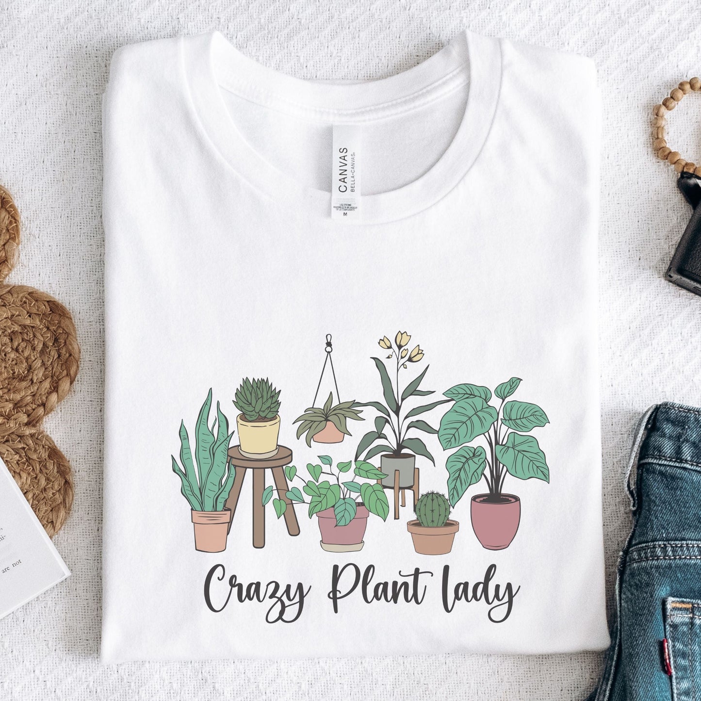 White t-shirt with plant illustration and 'Crazy Plant Lady' text on a textured surface.
