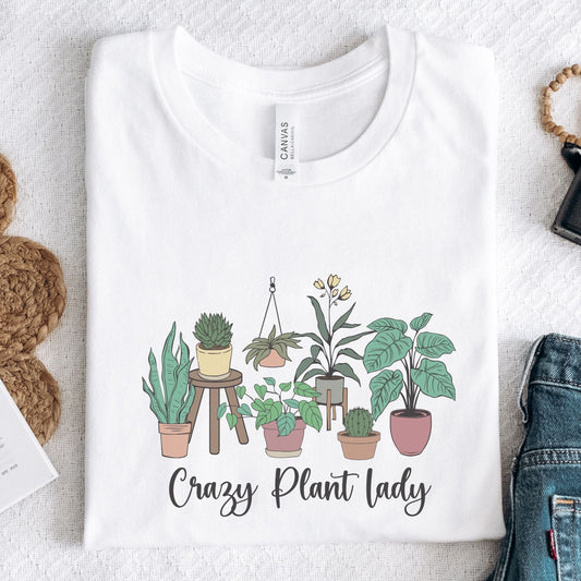 White t-shirt with plant illustration and 'Crazy Plant Lady' text on a textured surface.