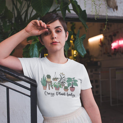 Person wearing a t-shirt with plant designs and text, standing indoors with plants in the background.