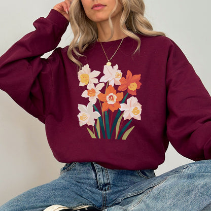Person wearing a maroon sweatshirt with floral design and blue jeans against a plain background