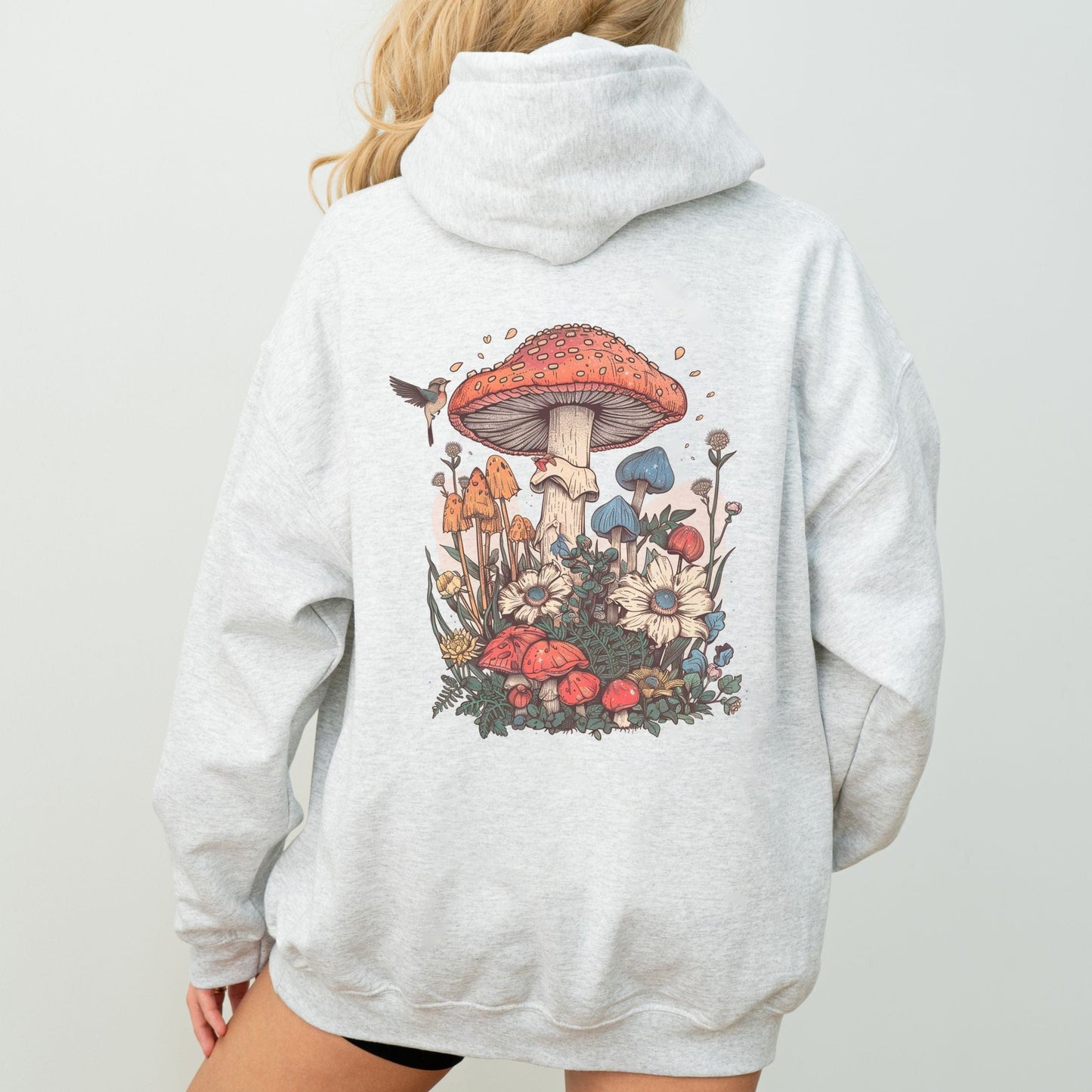 Person wearing an ash gray hoodie with a colorful mushroom and floral design on the back