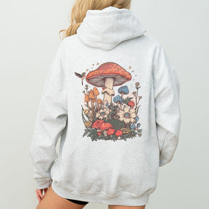 Person wearing an ash gray hoodie with a colorful mushroom and floral design on the back