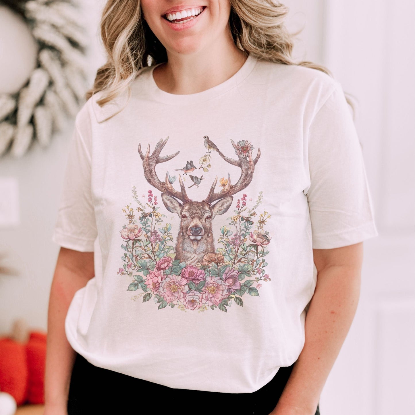 Person wearing a white t-shirt with a deer and floral design.