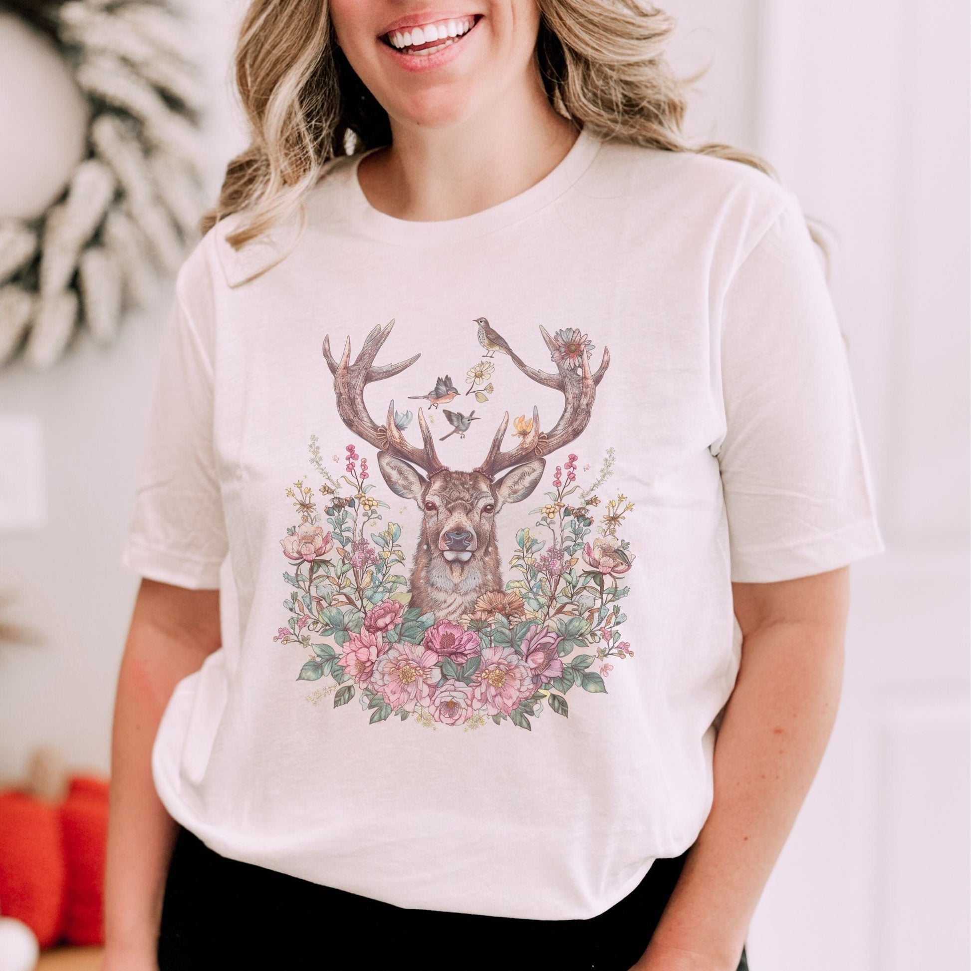 Person wearing a white t-shirt with a deer and floral design.