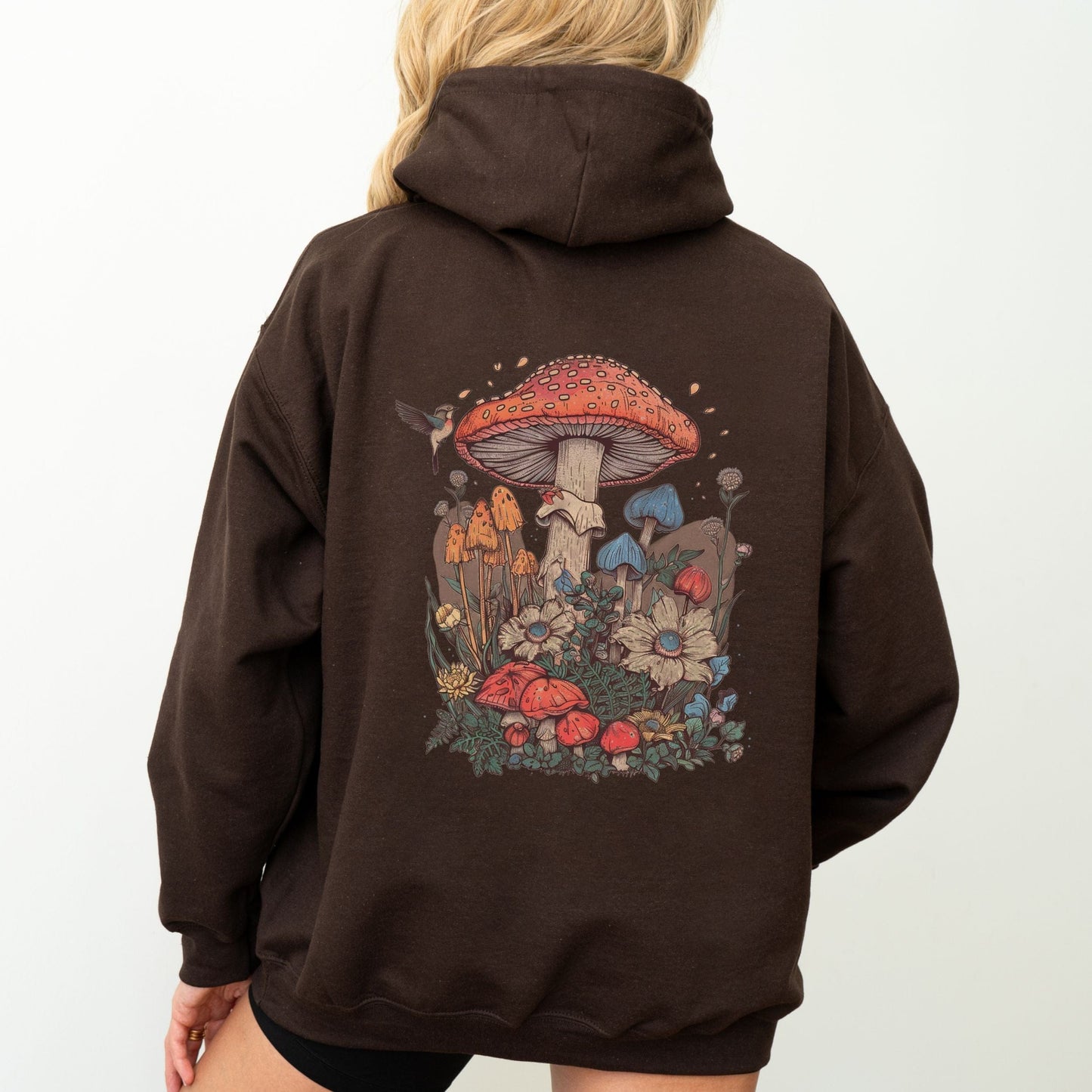 Brown hoodie with a colorful mushroom design on the back, worn by a person.