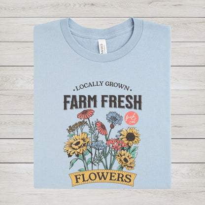 Light blue t-shirt with 'Farm Fresh Flowers' graphic on a wooden surface