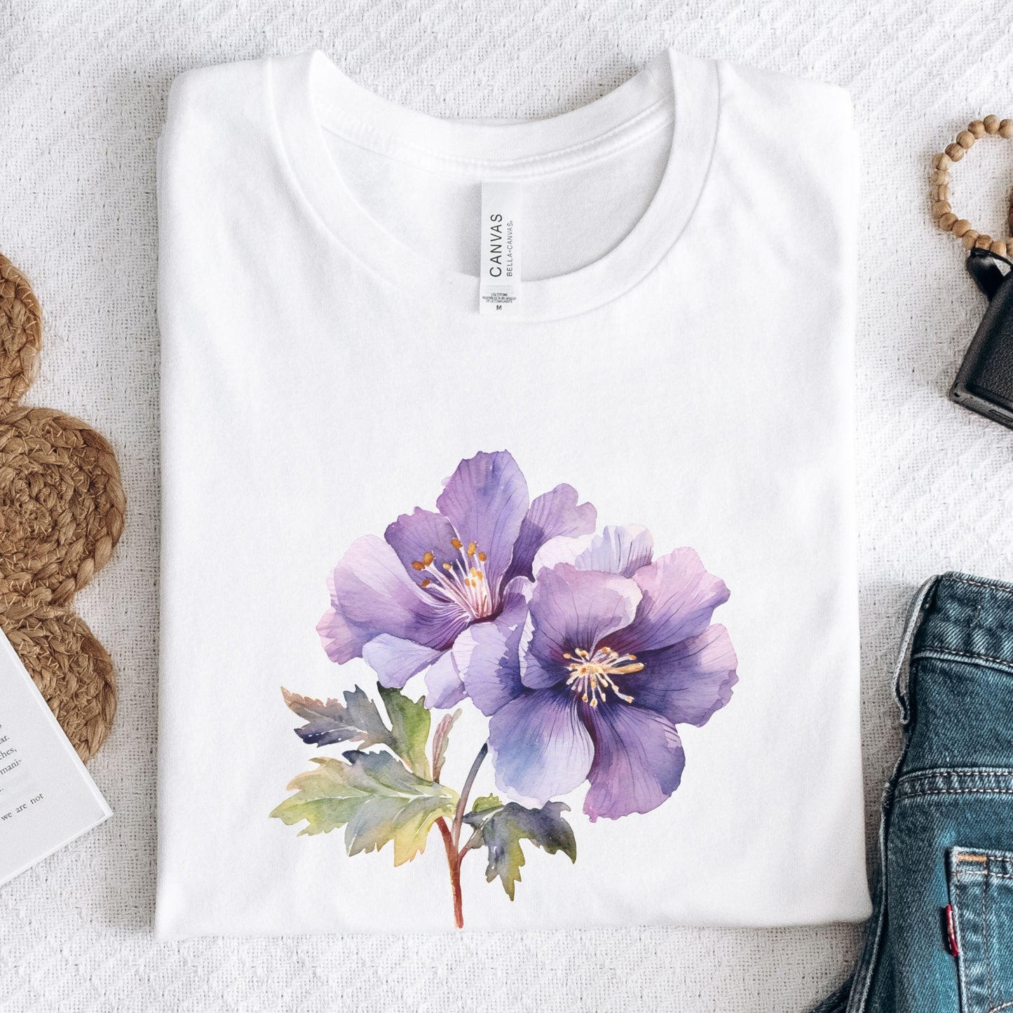 White t-shirt with a purple floral design on a textured surface.