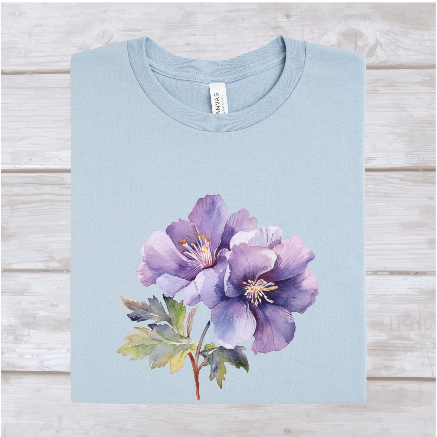 Light blue t-shirt with a purple floral design on a wooden surface