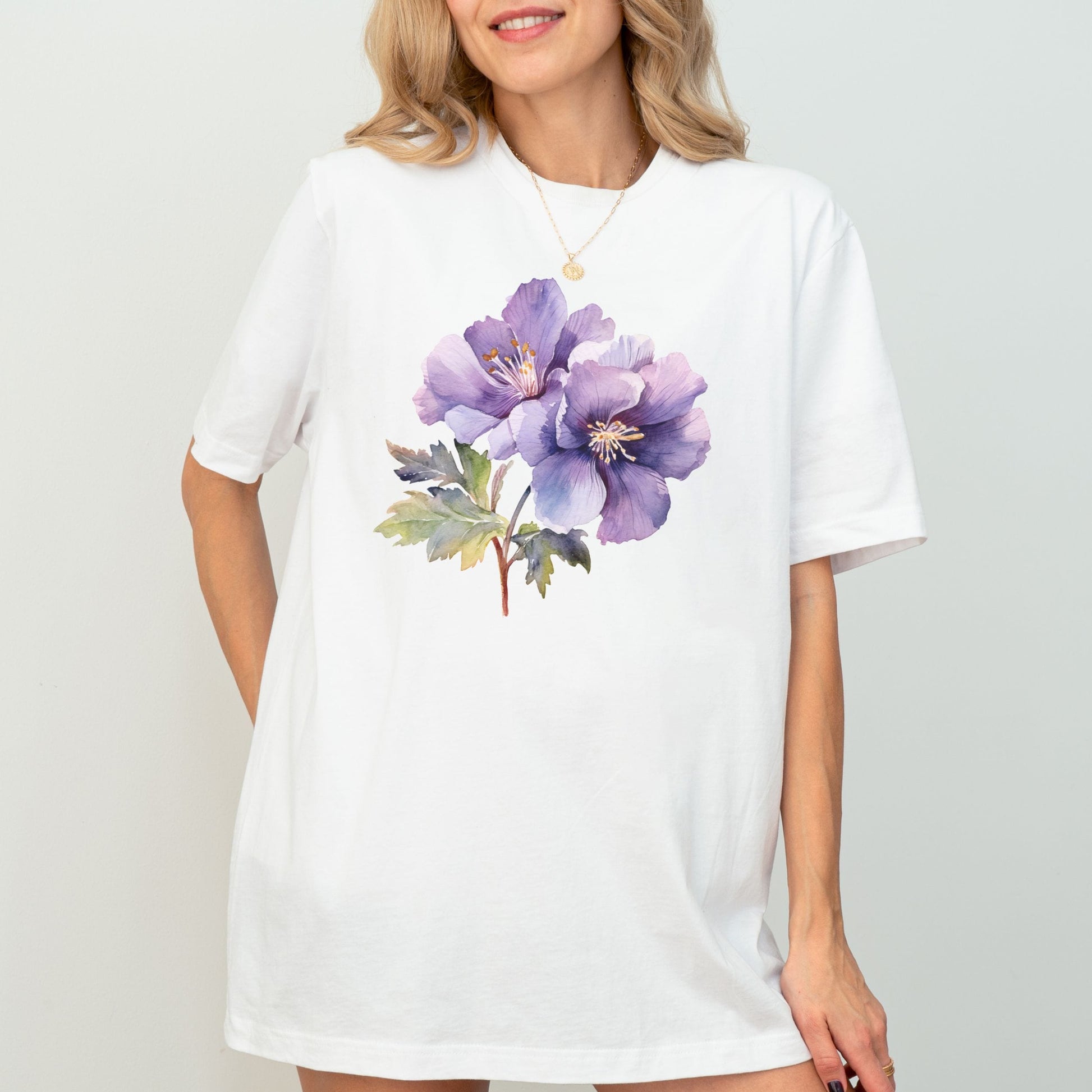 Woman wearing a white t-shirt with a purple floral design on a plain background