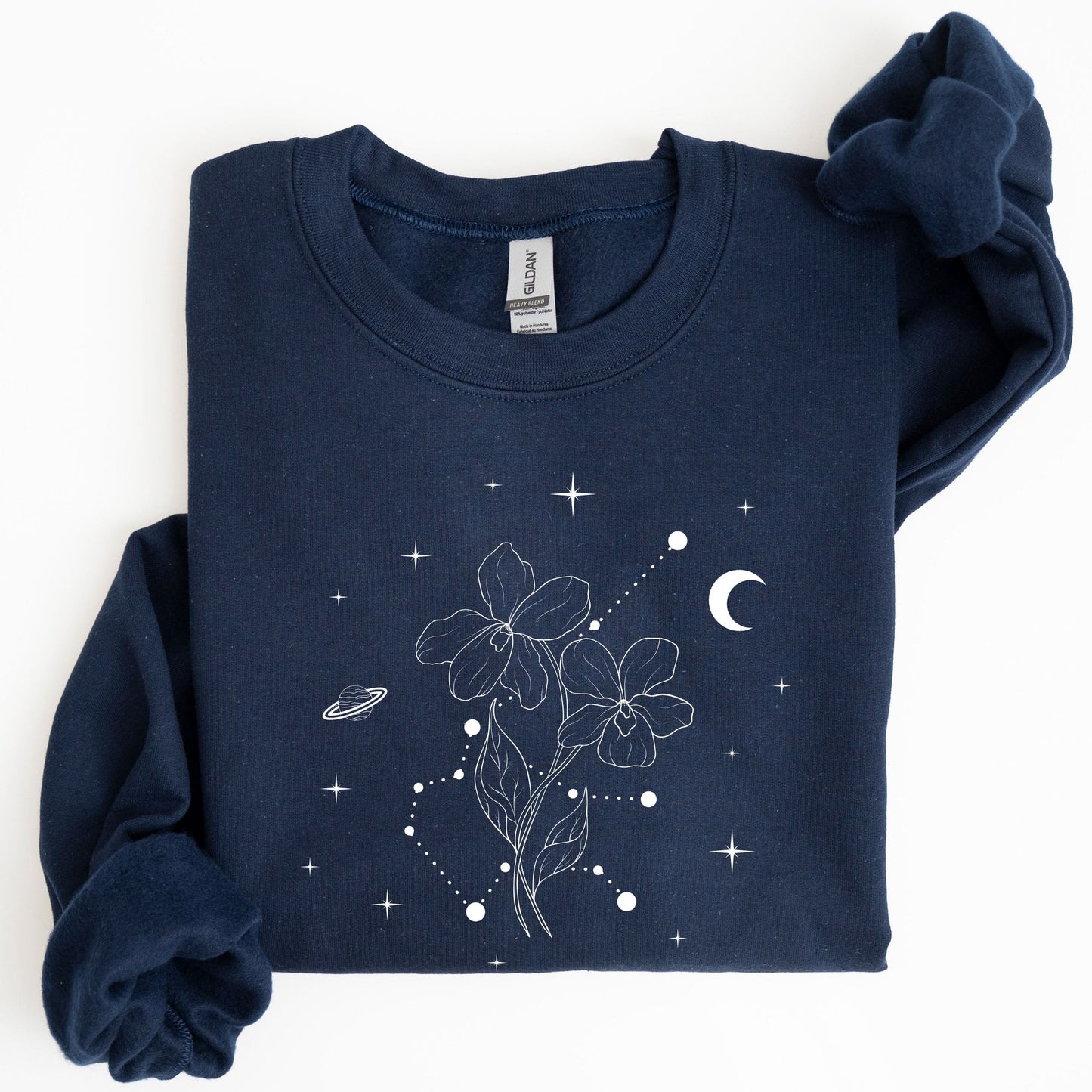 Folded navy blue sweatshirt with white floral and celestial design on a white background