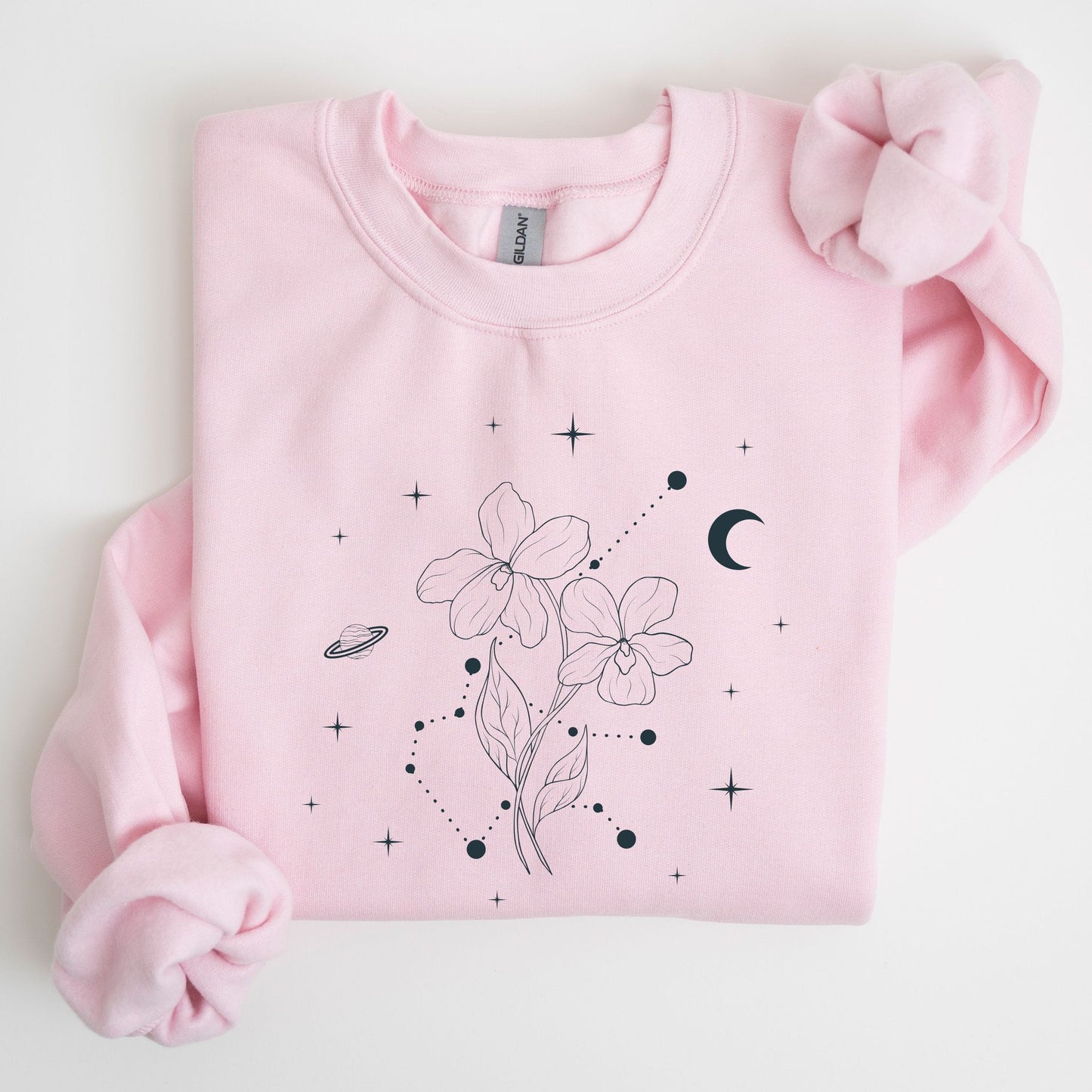 Pink sweatshirt with floral and celestial design on a light gray background