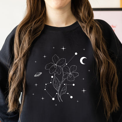 Person wearing a black sweatshirt with white floral and celestial design