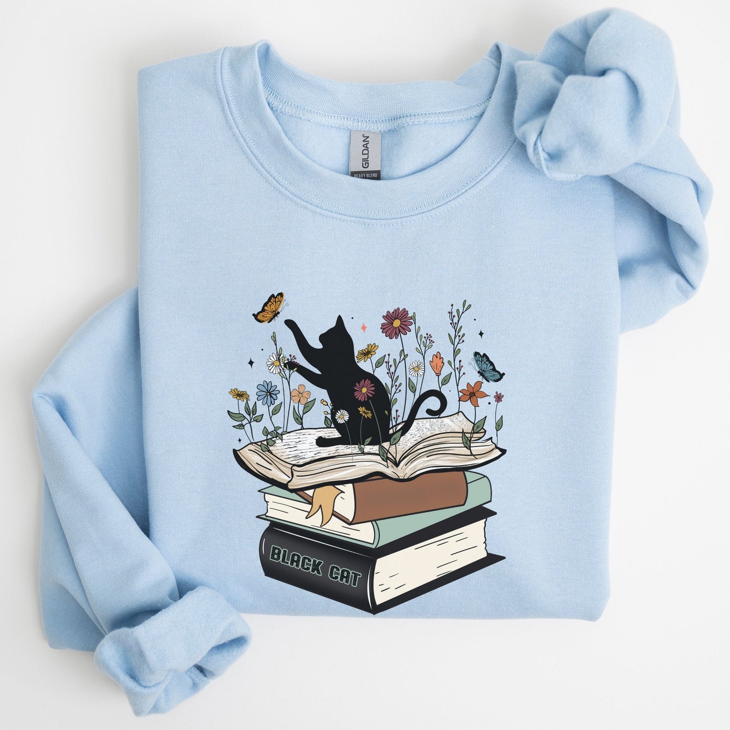 Light blue sweatshirt with a graphic of a black cat on books and flowers.