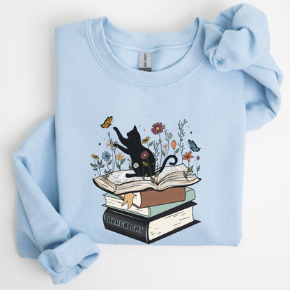 Light blue sweatshirt with a graphic of a black cat on books and flowers.