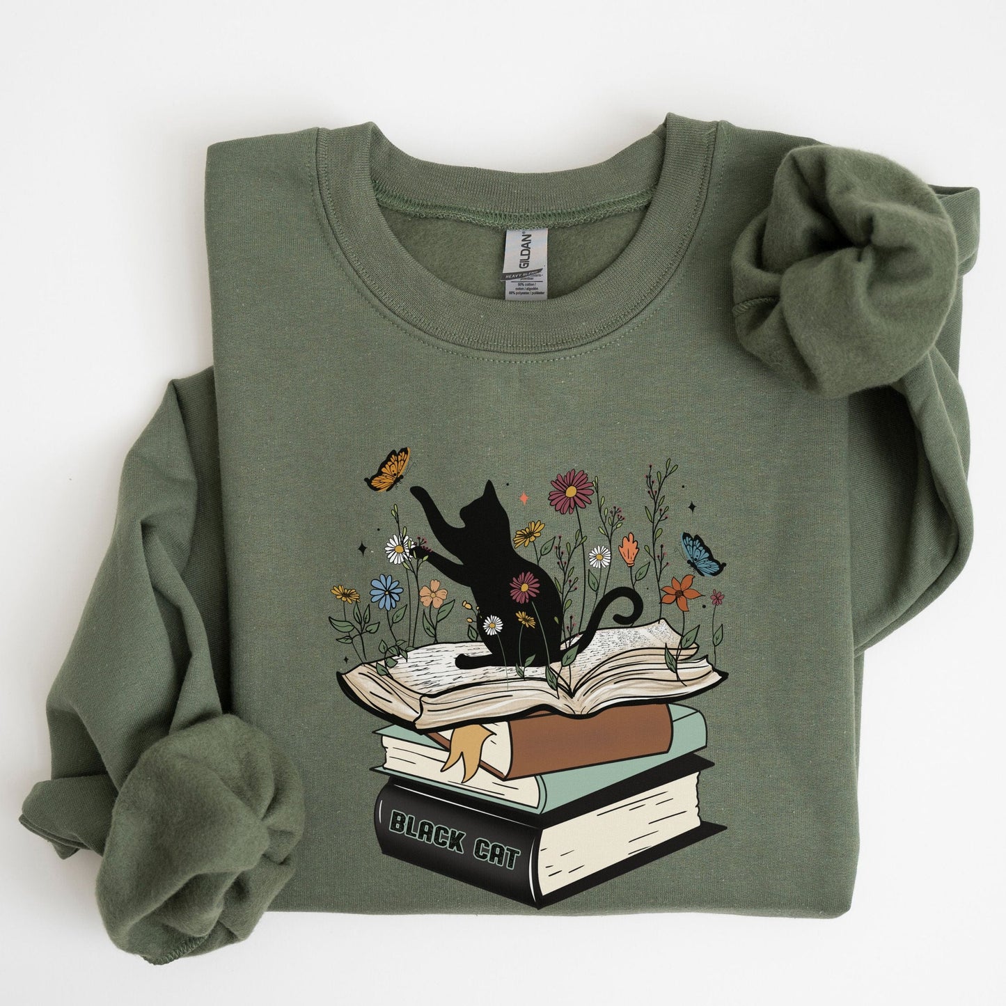 Green sweatshirt with a graphic of a black cat on books and flowers on a white background